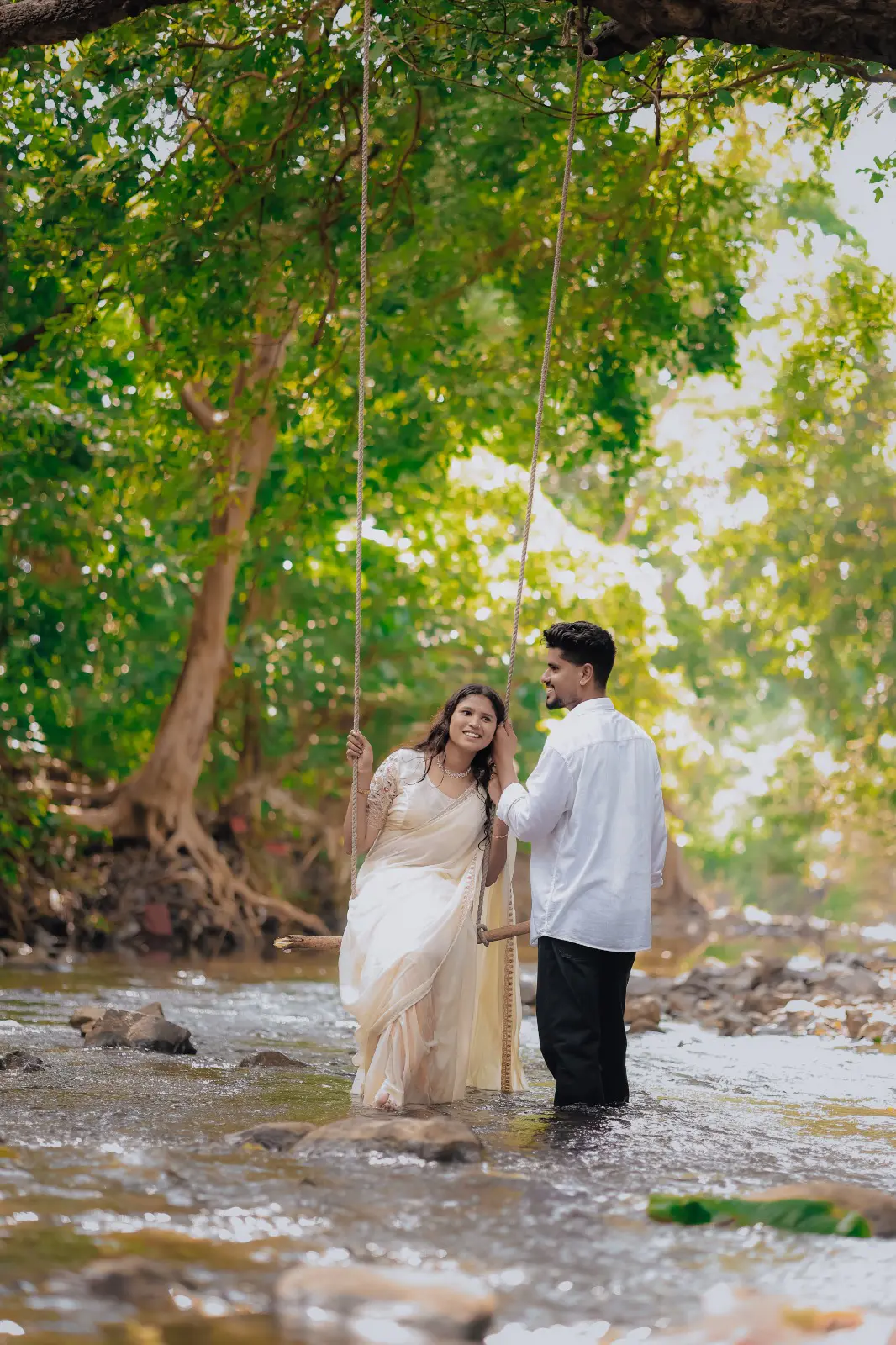 Pre-wedding couple on a rope swing in a forest stream