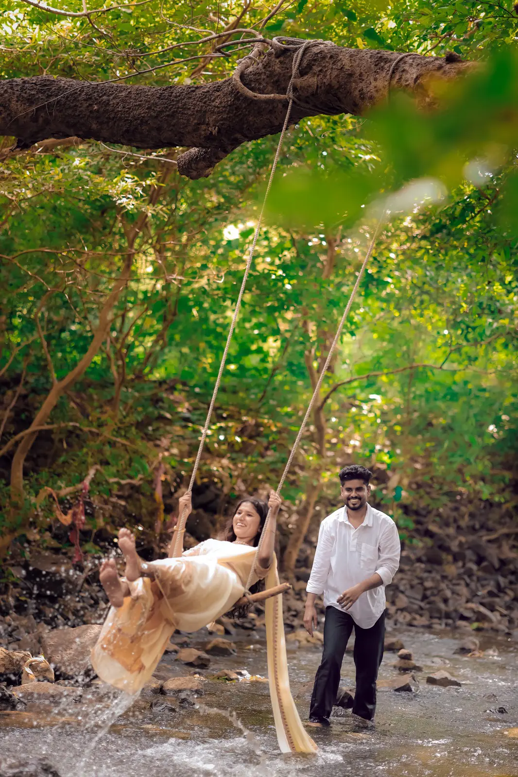 Pre-wedding couple enjoying a rope swing above a forest stream