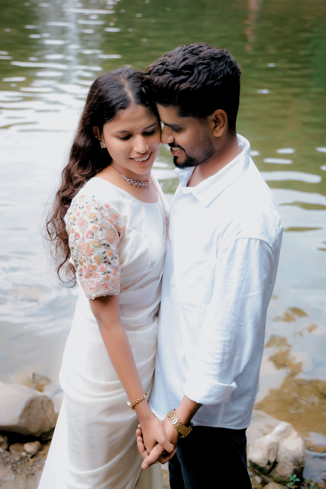 Pre-wedding couple holding hands beside a peaceful lake