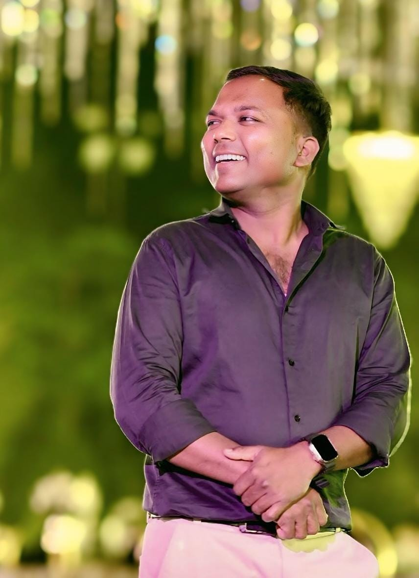 Manoj Badoliya smiling in his purple shirt at night