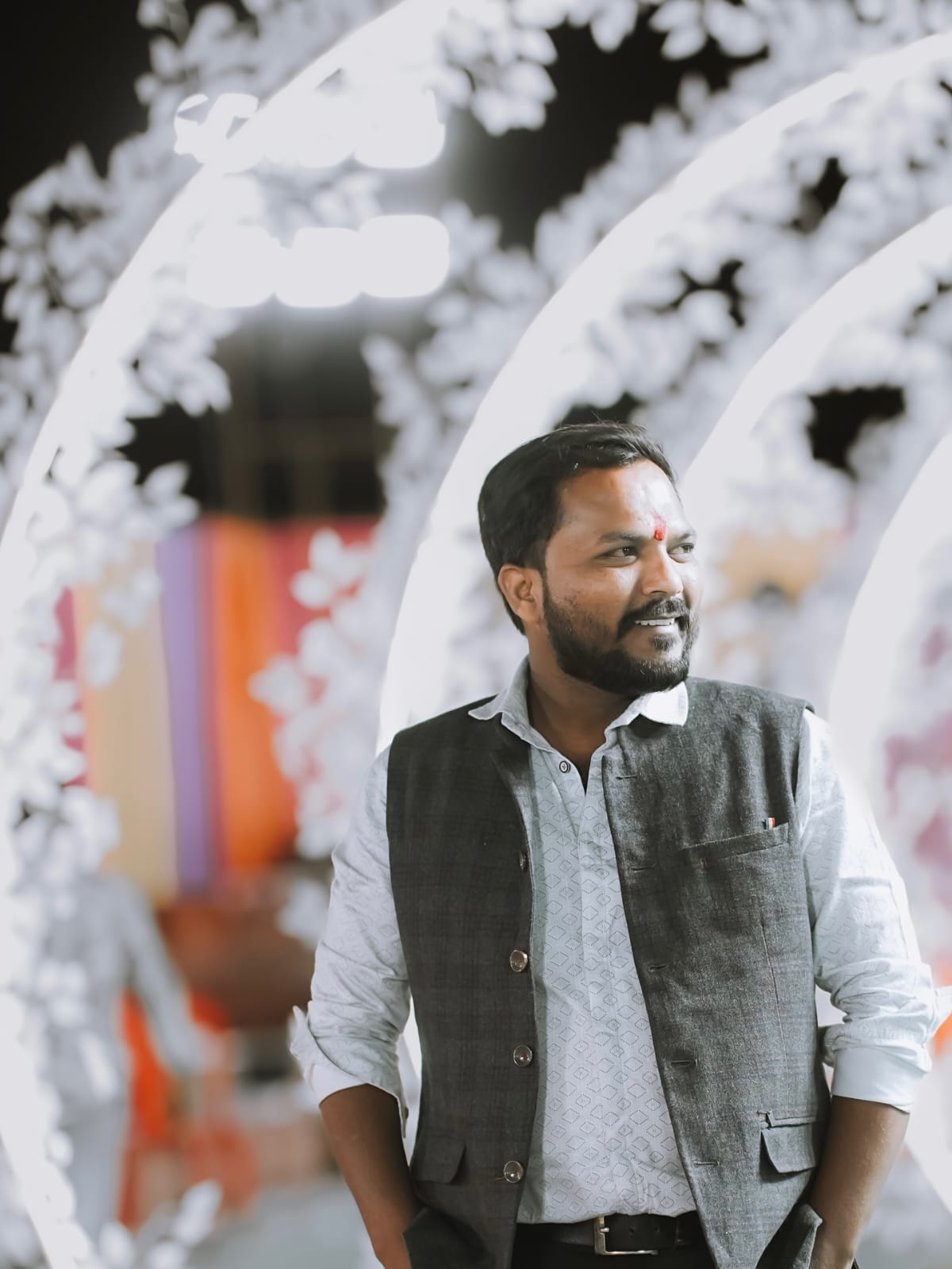 Manoj Badoliya in a grey vest at a decorated wedding venue